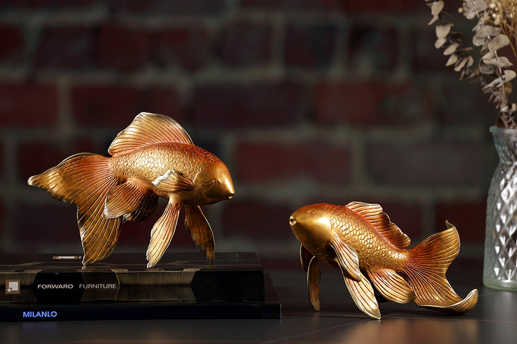 Two golden orange koi fish sculptures are on a desk in a home