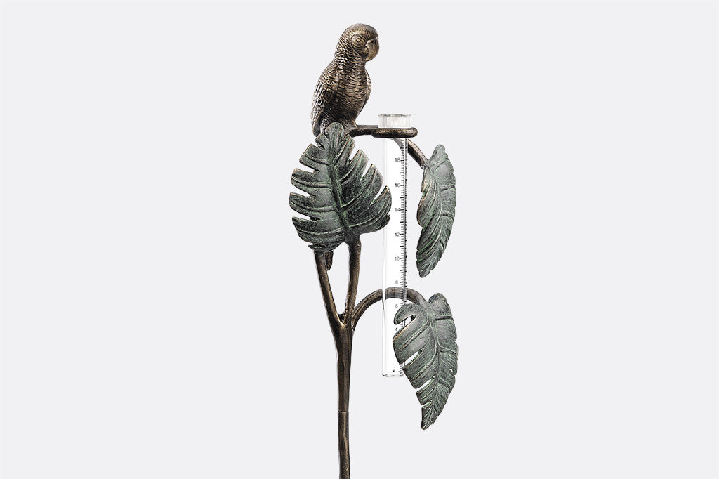 Sculptural rain catcher shaped like a Small parrot sitting on 3 tropical leaves