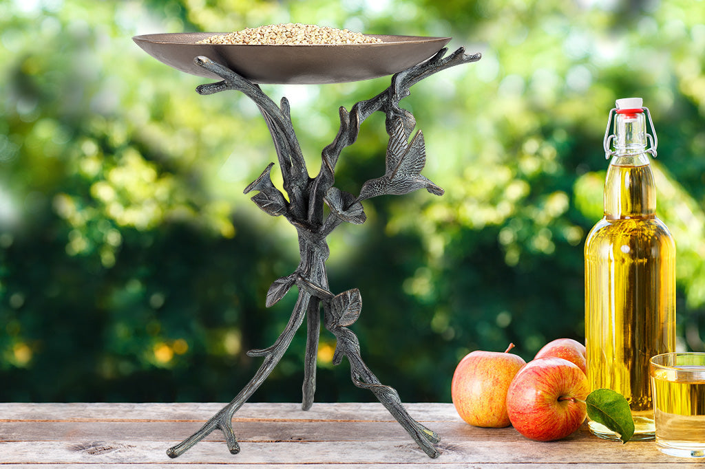 tabletop birdbath on table with apples and carafe of juice