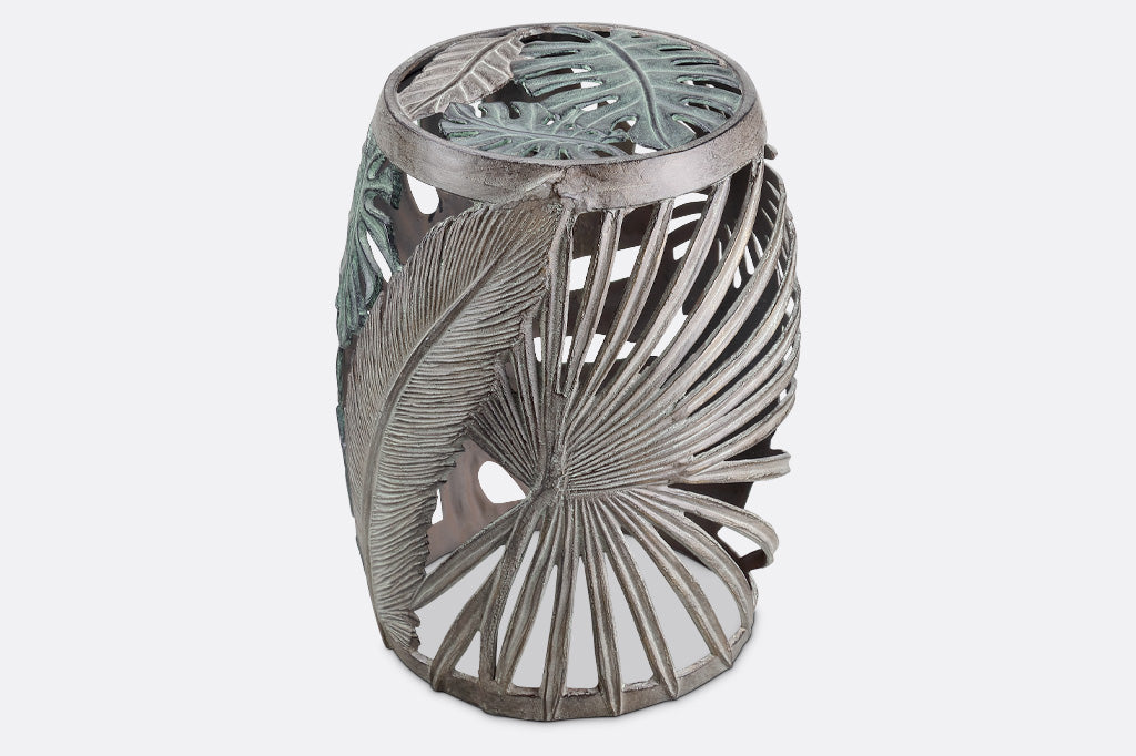 Las Palmas Garden Stool is adorned on all sides with a variety of hand sculpted tropical leaves. The leaves on this stool have been finished in verdigris and bronze over cast aluminum.