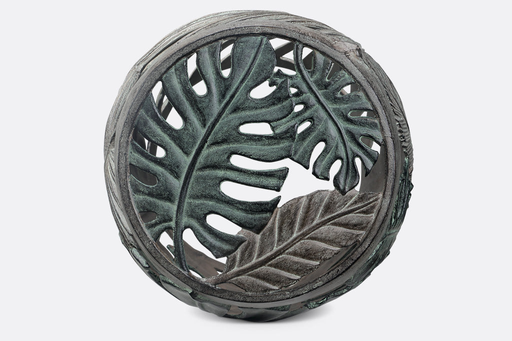 Top of Las Palmas Garden tool, features two monstera leaves in verdigris and another tropical leaf in contrast bronze. Circular stool.