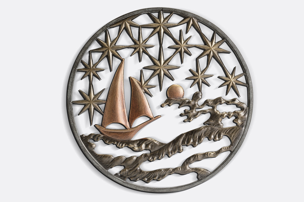 Cast metal circular wall plaque featuring 8-point stars, a moon, sea, and sailboat.