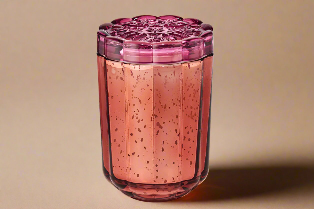 berry colored glass container with floral theme lid holds scented candle